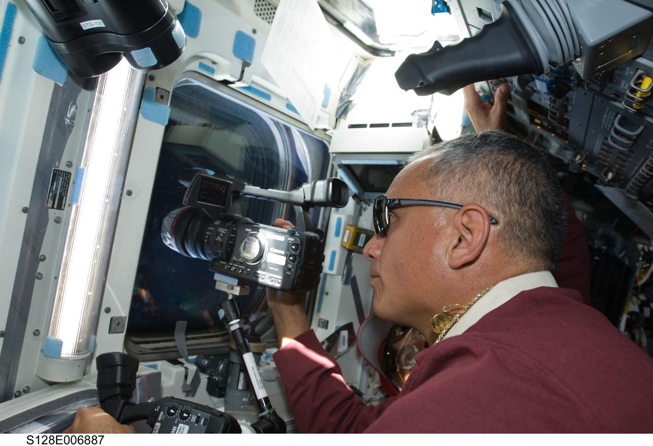 S128-E-006887 (30 Aug. 2009) --- Astronaut John “Danny” Olivas, STS-128 mission specialist, uses a High Definition Video (HDV) camera at an overhead window on the aft flight deck of Space Shuttle Discovery during flight day three activities.