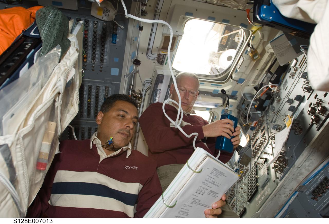 S128-E-007013 (30 Aug. 2009) --- Astronauts Jose Hernandez (left) and Patrick Forrester, both STS-128 mission specialists, work on the aft flight deck of Space Shuttle Discovery during flight day three activities.
