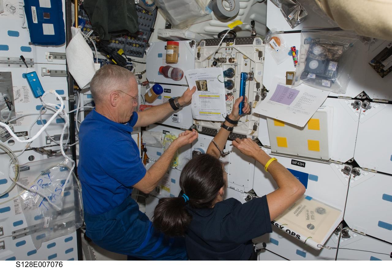 S128-E-007076 (31 Aug. 2009) --- Astronauts Patrick Forrester, STS-128 mission specialist; and Nicole Stott, Expedition 20 flight engineer, work on the middeck of Space Shuttle Discovery while docked with the International Space Station.