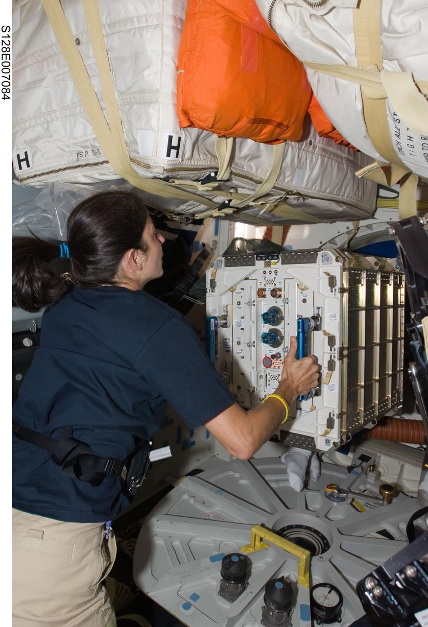 S128-E-007084 (31 Aug. 2009) --- Astronaut Nicole Stott, Expedition 20 flight engineer, prepares to move hardware through a hatch on the middeck of Space Shuttle Discovery (STS-128) while docked with the International Space Station.