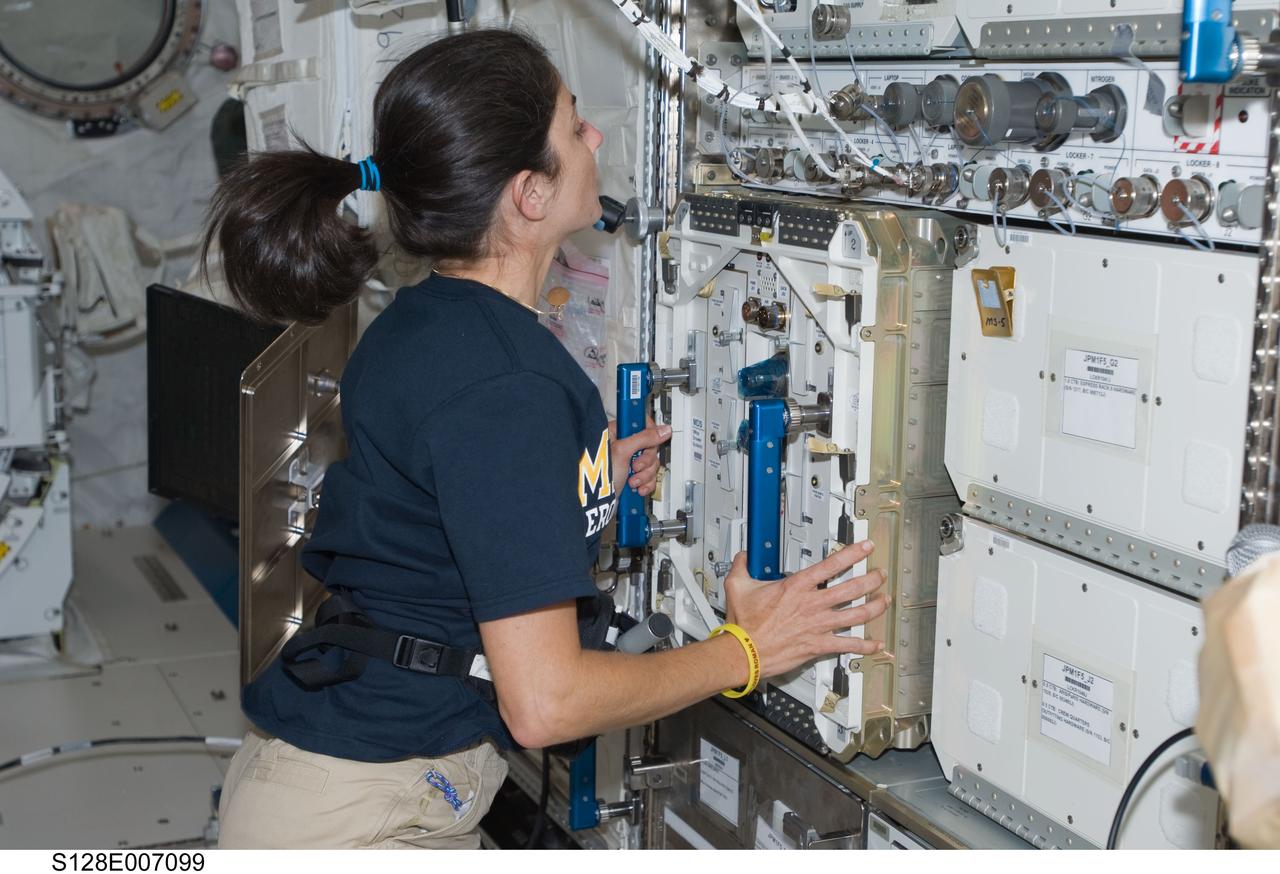 View of Nicole Stott as she works to transfer the Mice Drawer System (MDS) from the middeck (MDDK) of Discovery to the JEM Pressurized Module (JPM) during STS-128.
