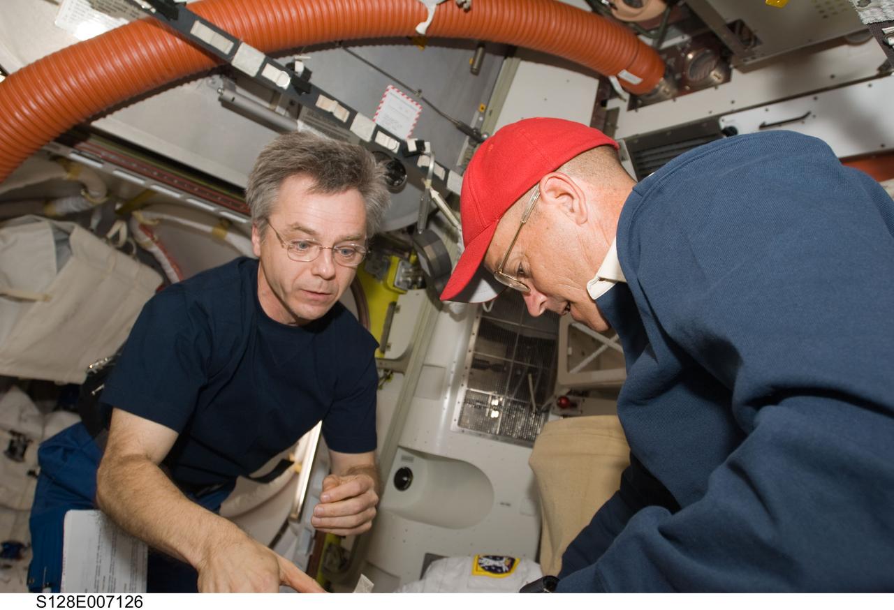 S128-E-007126 (31 Aug. 2009) --- NASA astronaut Rick Sturckow (right), STS-128 commander, and Canadian Space Agency astronaut Robert Thirsk, Expedition 20 flight engineer, work in the Quest airlock of the International Space Station while Space Shuttle Discovery remains docked with the station.