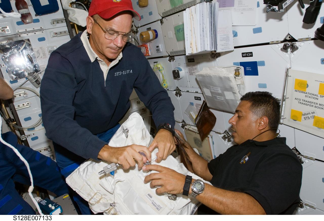 S128-E-007133 (31 Aug. 2009) --- Astronauts Rick Sturckow (left), STS-128 commander, and Jose Hernandez, mission specialist, work on the middeck of Space Shuttle Discovery while docked with the International Space Station.