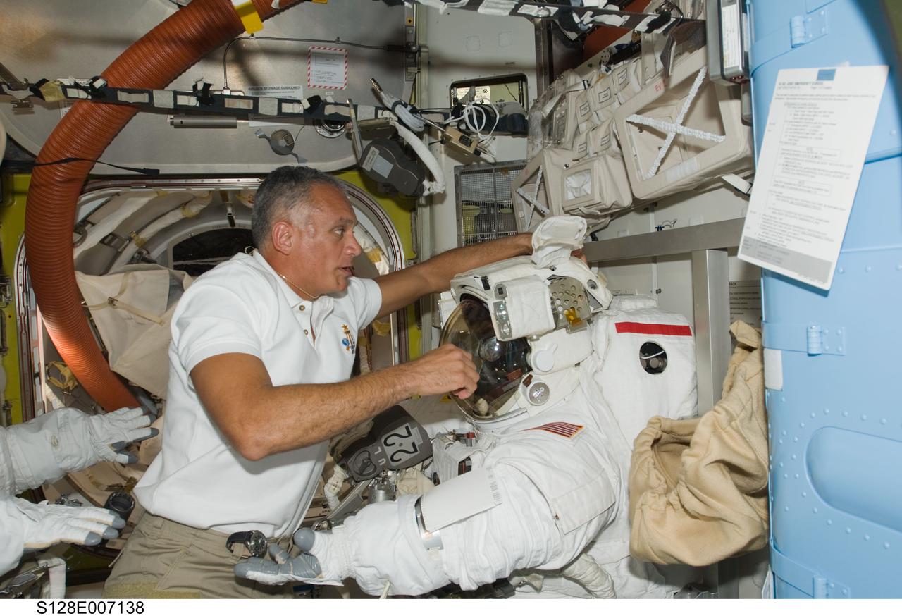 S128-E-007138 (31 Aug. 2009) --- Astronaut John “Danny” Olivas, STS-128 mission specialist, works near an Extravehicular Mobility Unit (EMU) spacesuit in the Quest airlock of the International Space Station while Space Shuttle Discovery remains docked with the station.