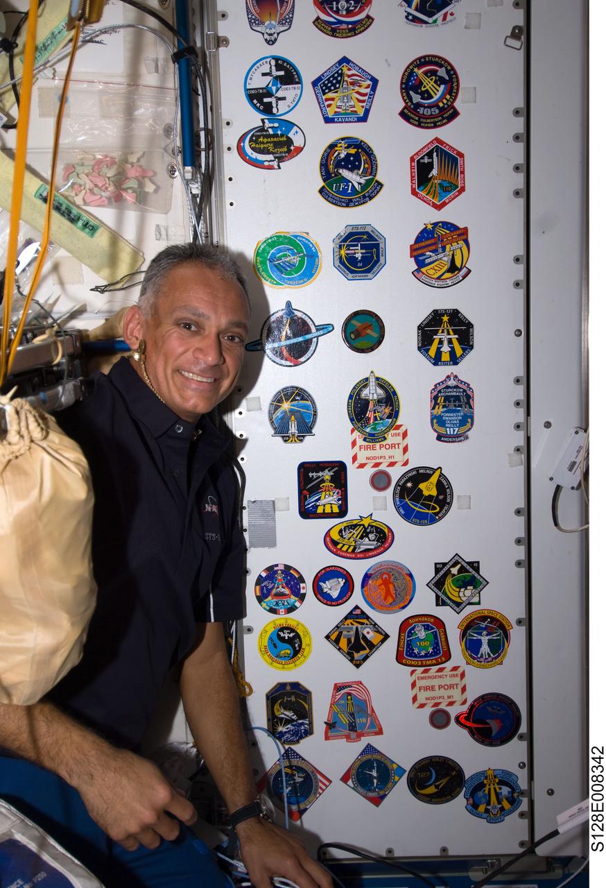 S128-E-008342 (7 Sept. 2009) --- NASA astronaut John “Danny” Olivas, STS-128 mission specialist, poses for a photo with the growing collection, in the Unity node, of insignias representing crews who have worked on the International Space Station.