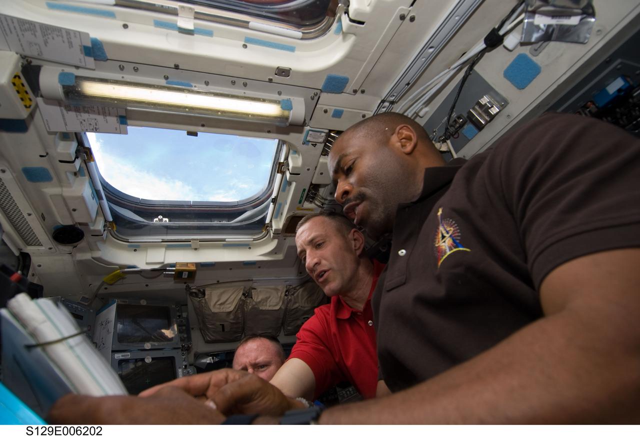 S129-E-006202 (17 Nov. 2009) --- Astronauts Leland Melvin (foreground), STS-129 mission specialist; Charles O. Hobaugh, commander; and Barry E. Wilmore, pilot, work on the aft flight deck of Space Shuttle Atlantis during flight day two activities.