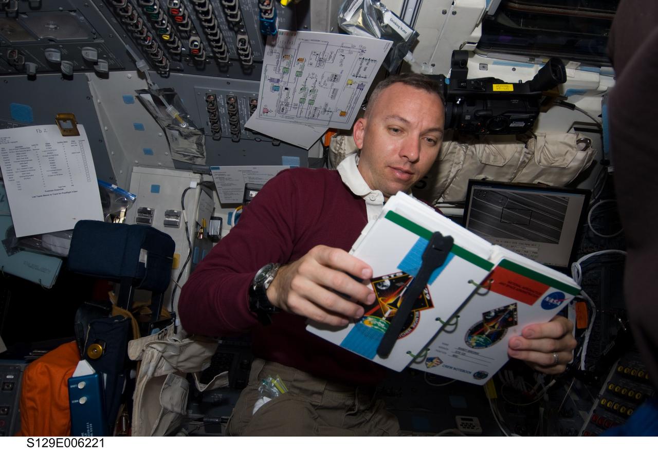 S129-E-006221 (17 Nov. 2009) --- Astronaut Randy Bresnik, STS-129 mission specialist, reads his crew notebook on the aft flight deck of Space Shuttle Atlantis during flight day two activities.
