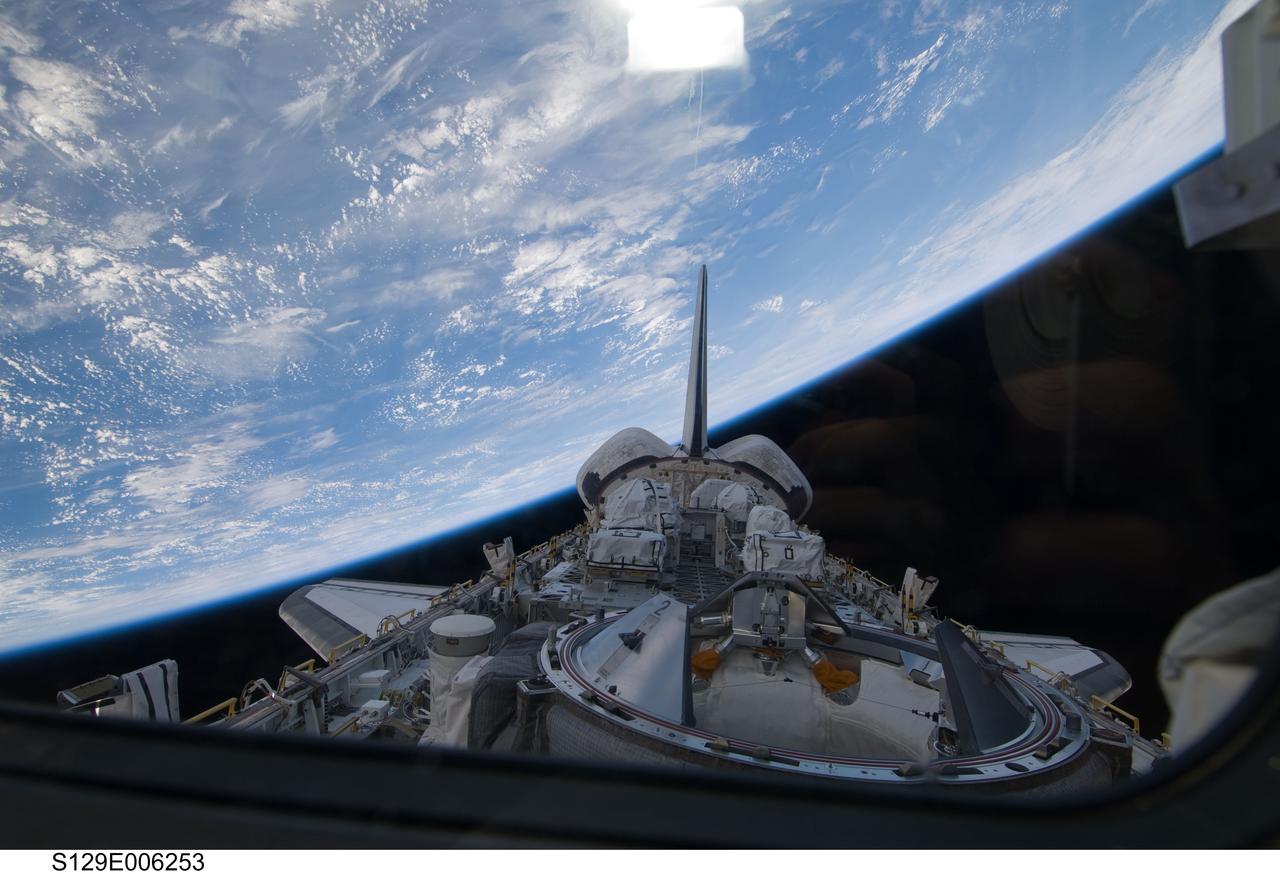 S129-E-006253 (17 Nov. 2009) --- Backdropped by Earth?s horizon and the blackness of space, a partial view of Space Shuttle Atlantis? payload bay, vertical stabilizer, orbital maneuvering system (OMS) pods and docking mechanism are featured in this image photographed by an STS-129 crew member from an aft flight deck window.