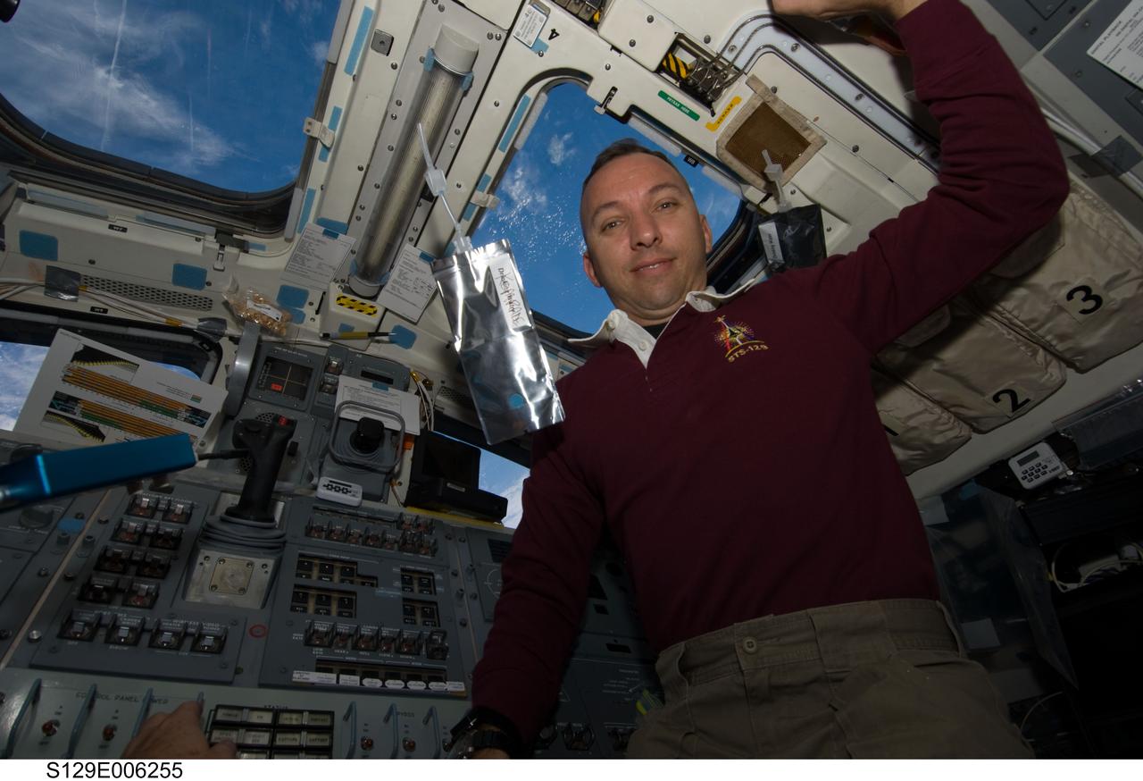 S129-E-006255 (17 Nov. 2009) --- Astronaut Randy Bresnik, STS-129 mission specialist, is pictured near a beverage container floating freely on the aft flight deck of Space Shuttle Atlantis during flight day two activities.