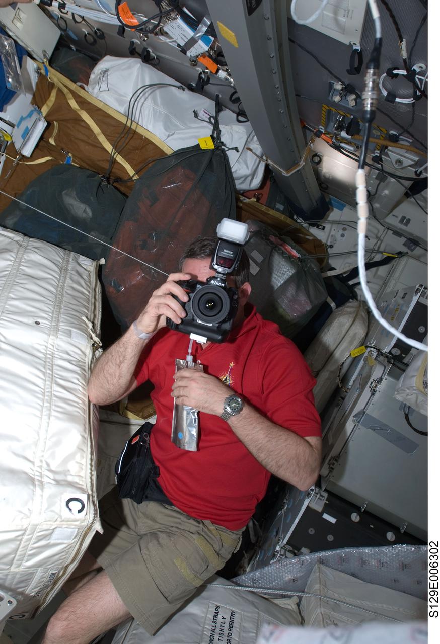 S129-E-006302 (17 Nov. 2009) --- Astronaut Mike Foreman, STS-129 mission specialist, uses a still camera on the middeck of Space Shuttle Atlantis during flight day two activities.