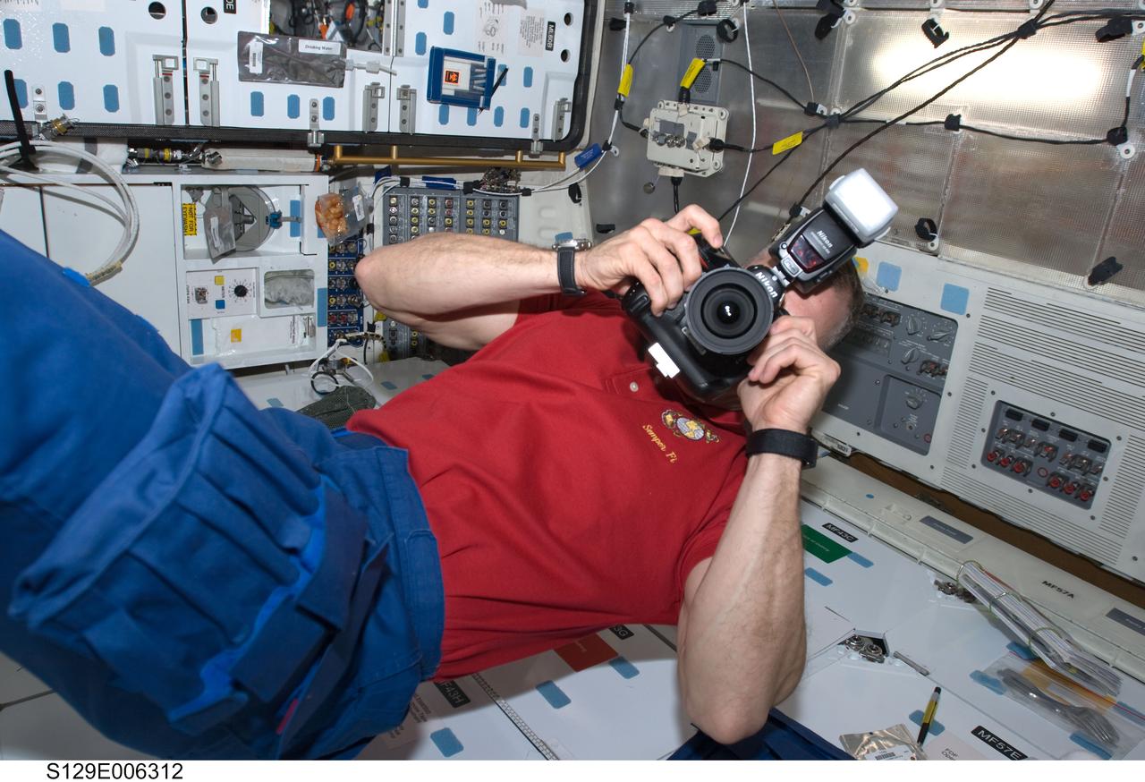 S129-E-006312 (17 Nov. 2009) --- Astronaut Charles O. Hobaugh, STS-129 commander, uses a still camera on the middeck of Space Shuttle Atlantis during flight day two activities.