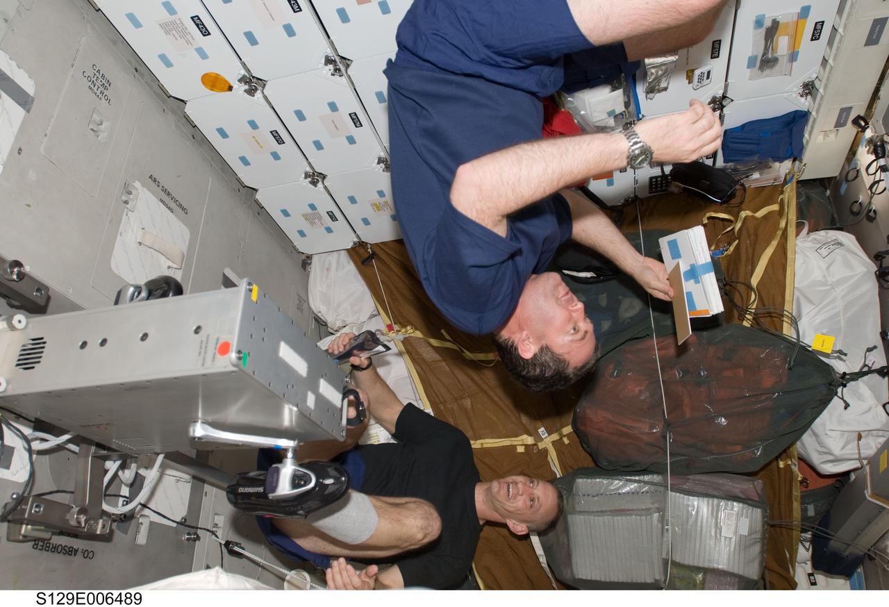 S129-E-006489 (17 Nov. 2009) --- Astronauts Charles O. Hobaugh (bottom), STS-129 commander; and Mike Foreman, mission specialist, are pictured on the middeck of Space Shuttle Atlantis during flight day two activities. Hobaugh is exercising on a bicycle ergometer.