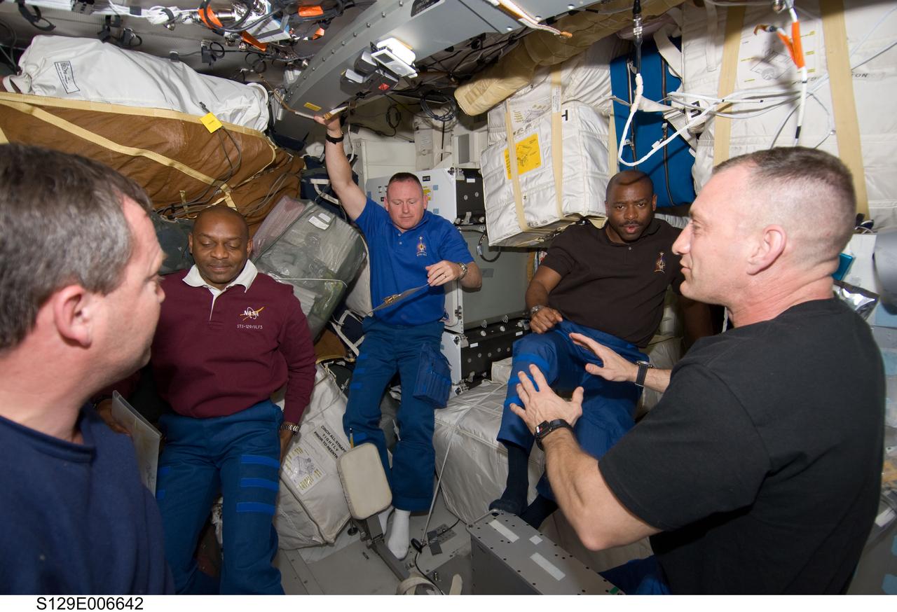 S129-E-006642 (17 Nov. 2009) --- Astronaut Charles O. Hobaugh (right), STS-129 commander, briefs his crew on the middeck of Space Shuttle Atlantis during flight day two activities. Pictured from the left are astronauts Mike Foreman, Robert L. Satcher Jr., both mission specialists; Barry E. Wilmore, pilot; and Leland Melvin, mission specialist. Not pictured is astronaut Randy Bresnik, mission specialist.