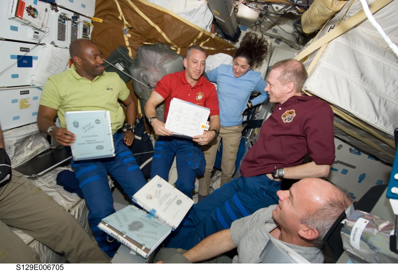 S129-E-006705 (18 Nov. 2009) --- On Atlantis? middeck, from left, astronauts Leland Melvin, Charles Hobaugh, Nicole Stott, Frank De Winne  and Jeffrey Williams discuss their roles for flight day three activities.  De Winne represents the European Space Agency. DeWinne and Williams are station crew members, while Hobaugh, Melvin and Stott are members of the STS-129 crew.