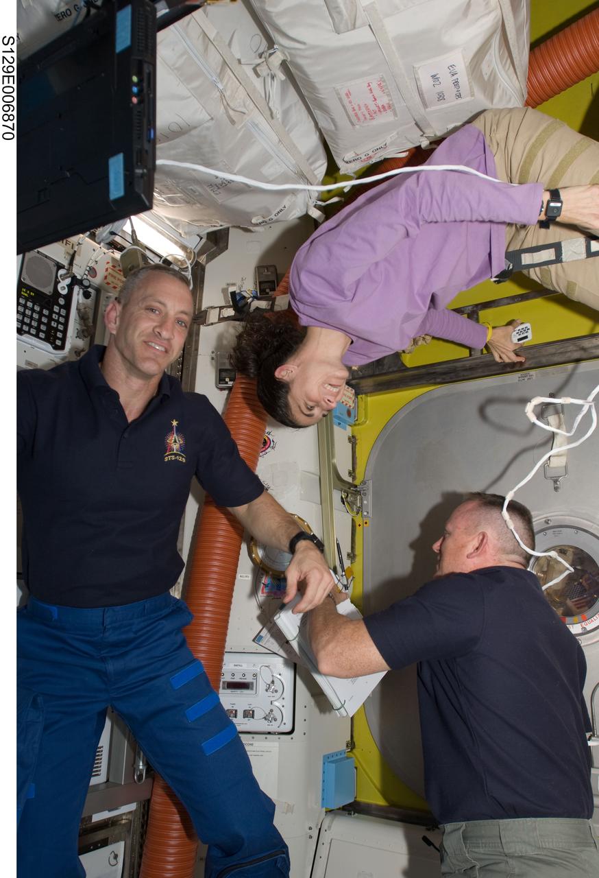 S129-E-006870 (19 Nov. 2009) --- Astronauts Charles O. Hobaugh (left), STS-129 commander; Nicole Stott, mission specialist; and Barry E. Wilmore, pilot, are pictured in the Quest airlock of the International Space Station after closing the hatch to begin the mission?s first spacewalk.