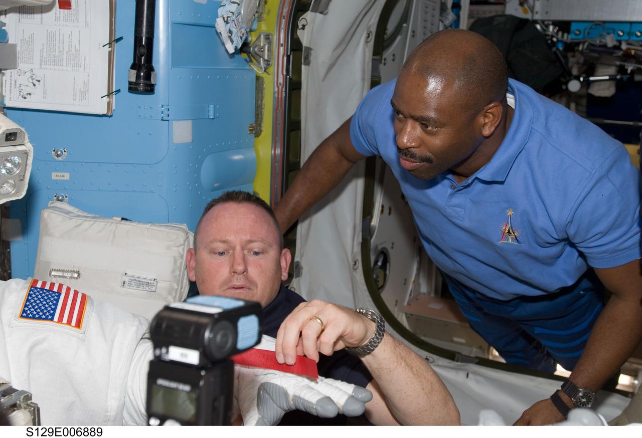 S129-E-006889 (19 Nov. 2009) --- Astronauts Barry E. Wilmore (left), STS-129 pilot, and Leland Melvin, mission specialist, work in the shirt-sleeve environment of the docked  International Space Station and Space Shuttle Atlantis to support the flight day four space walk of crewmates Mike Foreman and Robet L. Satcher Jr.