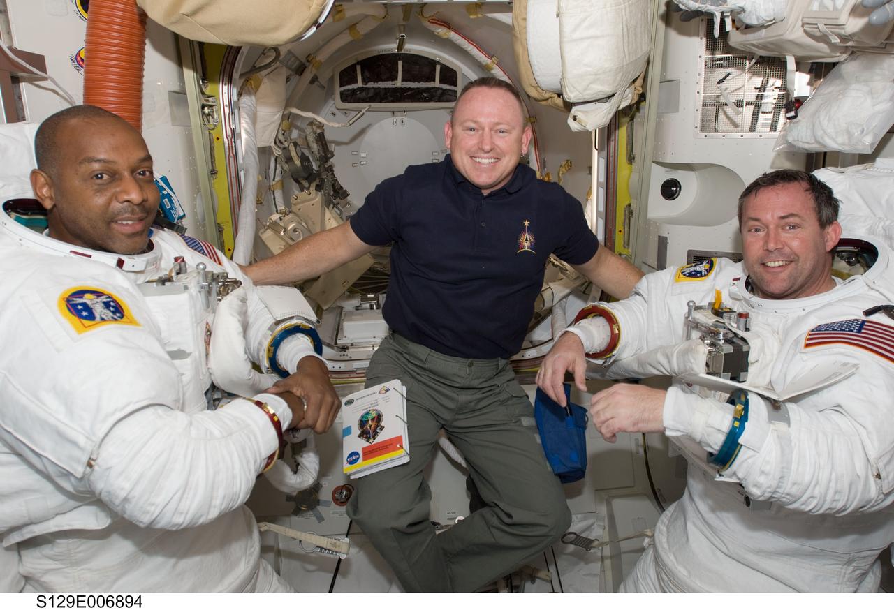 S129-E-006894 (19 Nov. 2009) --- In the Quest airlock, astronaut Barry E. Wilmore (center), STS-129 pilot,  assists crewmates Robert L. Satcher Jr. (left) and Mike Foreman, mission specialists,  in getting ready for their flight day four space walk.