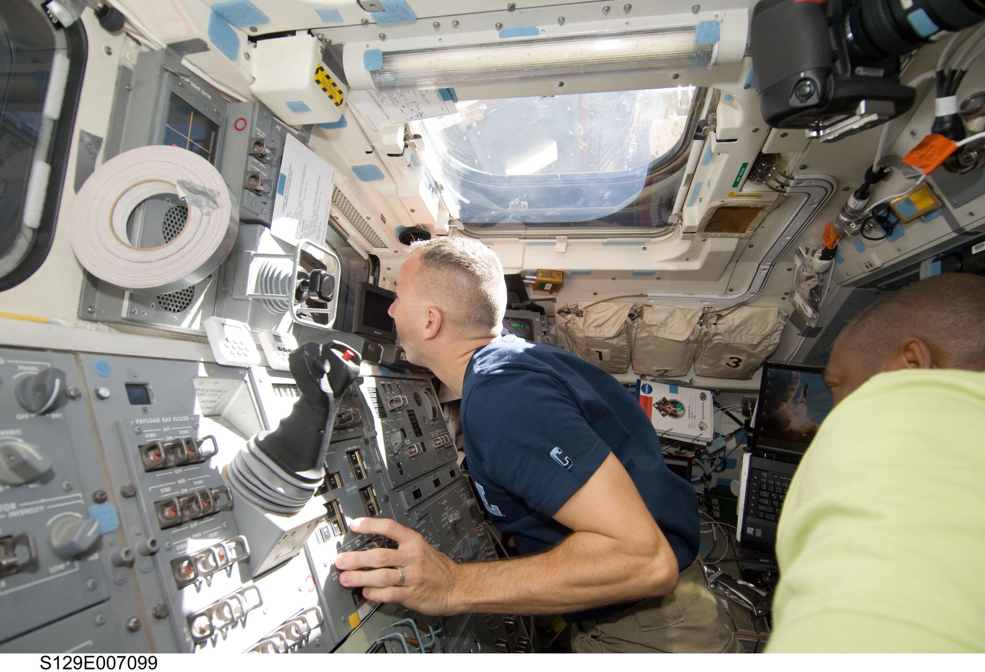 Astronaut Randy Bresnik, STS-129 mission specialist, works controls on the aft flight deck of Space Shuttle Atlantis during flight day three activities.
