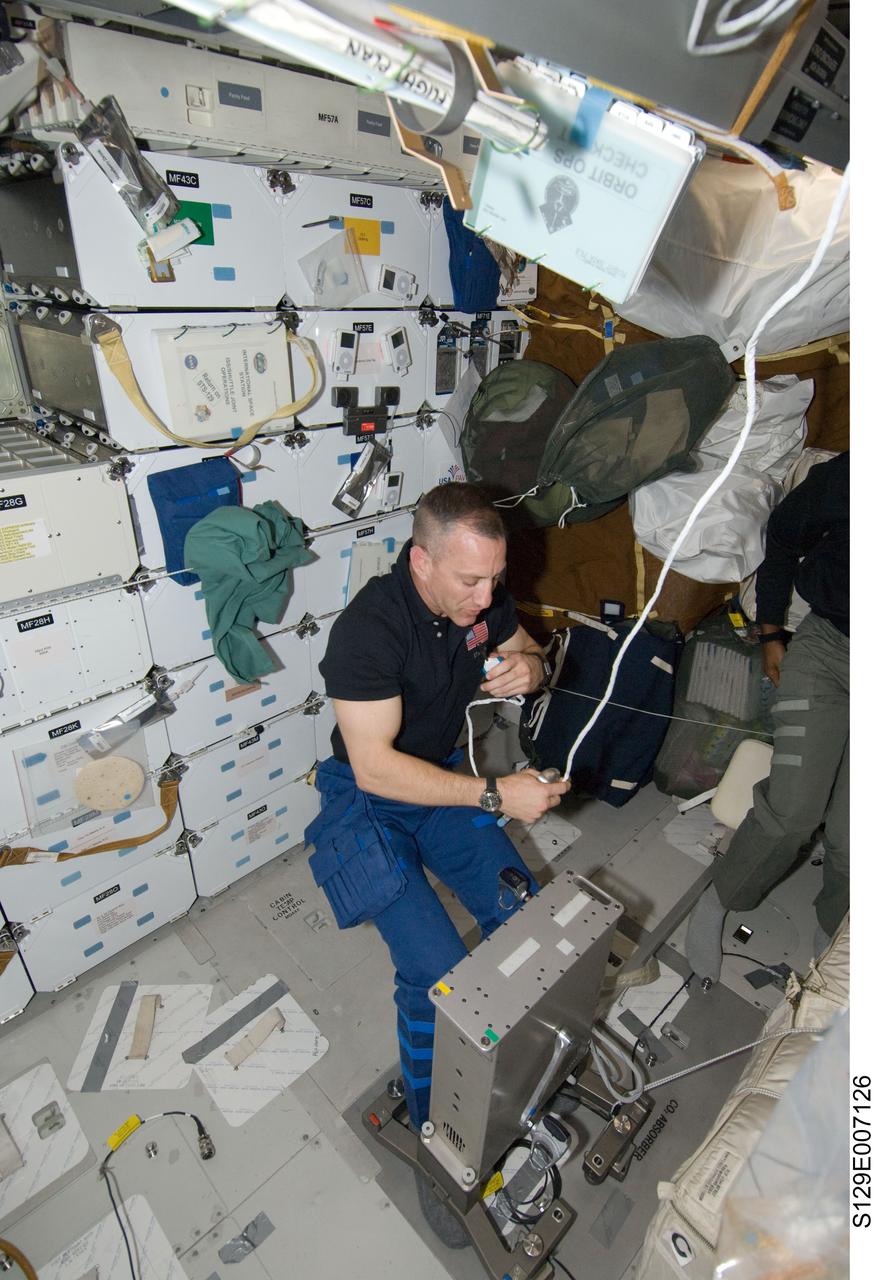 S129-E-007126 (20 Nov. 2009) --- Astronaut Charles O. Hobaugh, STS-129 commander, uses a communication system on the middeck of Space Shuttle Atlantis while docked with the International Space Station.