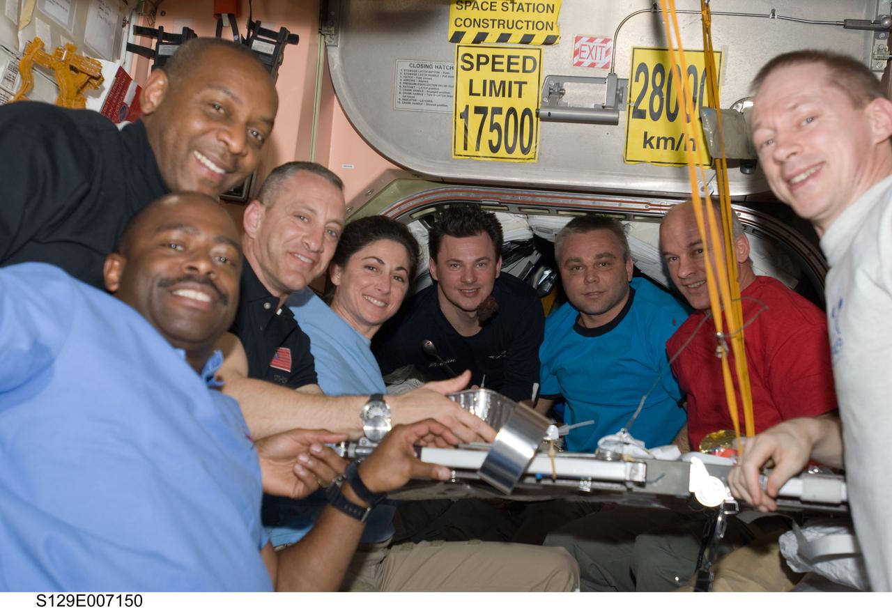 S129-E-007150 (20 Nov. 2009) --- Eight of the 12 crew members currently on the International Space Station pose for a photo at the galley in the Unity node while Space Shuttle Atlantis remains docked with the station. Pictured from the left are NASA astronauts Leland Melvin, Robert L. Satcher Jr., both STS-129 mission specialists; Charles O. Hobaugh, STS-129 commander; Nicole Stott, STS-129 mission specialist; Russian cosmonauts Roman Romanenko and Maxim Suraev and NASA astronaut Jeffrey Williams, all Expedition 21 flight engineers; and European Space Agency astronaut Frank De Winne, Expedition 21 commander.