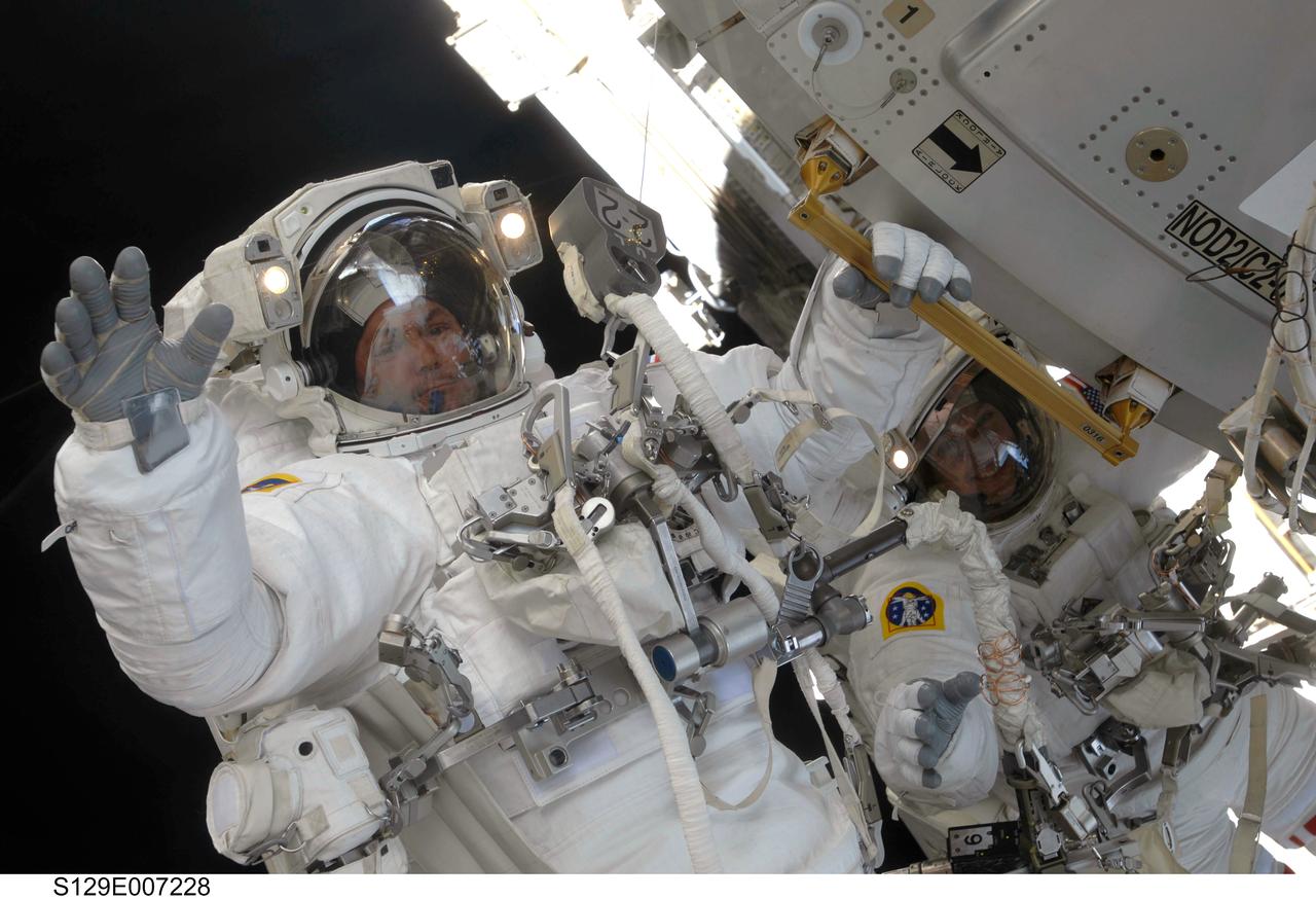 S129-E-007228 (21 Nov. 2009) --- Astronaut Mike Foreman, STS-129 mission specialist,  waves at a camera-bearing crewmate during the second spacewalk of Atlantis’ visit to the International Space Station. Astronaut Randy Bresnik is seen on the right side of the frame. Foreman holds onto a handrail on the U.S. Node 2 or Harmony.