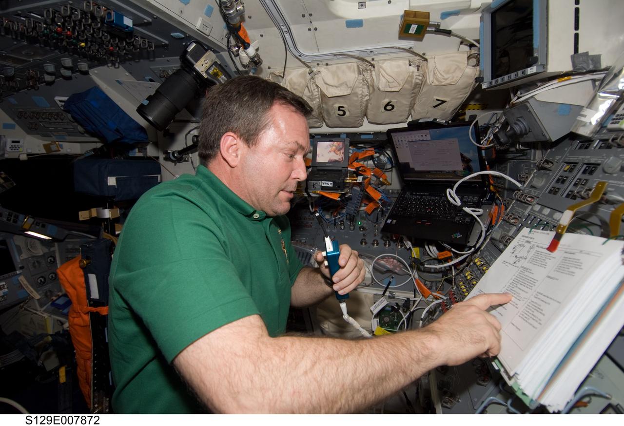 S129-E-007872 (23 Nov. 2009) --- Astronaut Mike Foreman, STS-129 mission specialist, uses a communication system on the aft flight deck of space shuttle Atlantis while docked with the International Space Station.