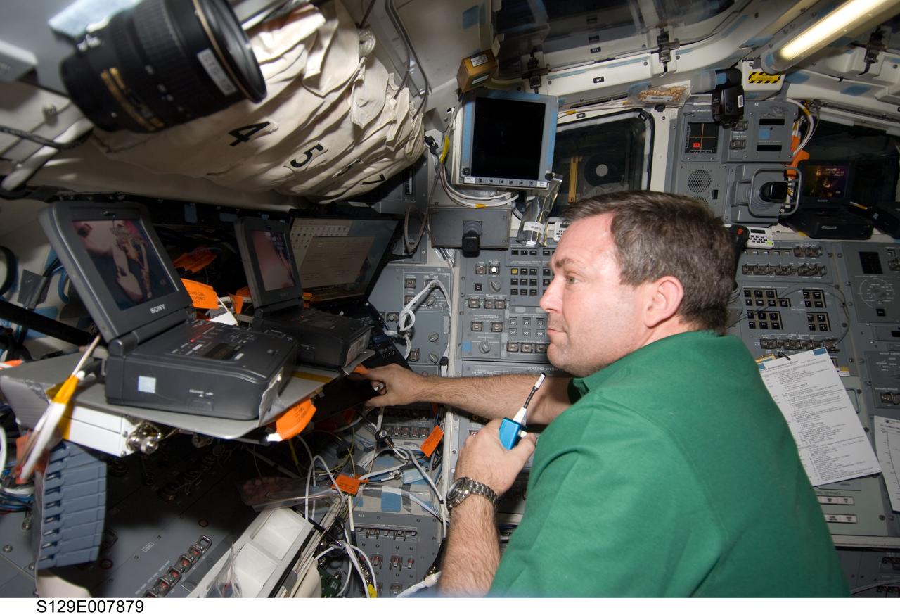 S129-E-007879 (23 Nov. 2009) --- Astronaut Mike Foreman, STS-129 mission specialist, uses a communication system on the aft flight deck of space shuttle Atlantis while docked with the International Space Station.