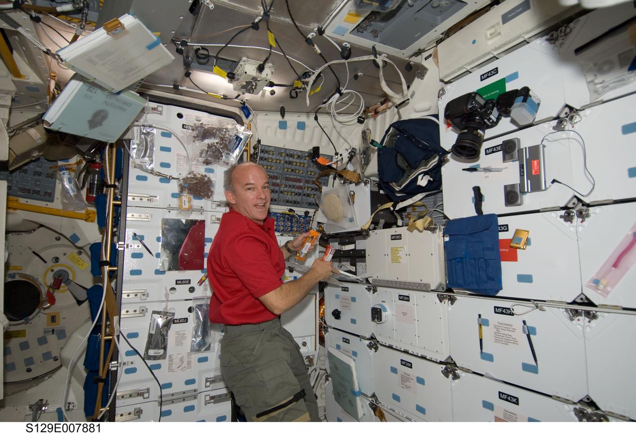 S129-E-007881 (23 Nov. 2009) --- Astronaut Jeffrey Williams, Expedition 21 flight engineer, prepares to eat a snack on the middeck of space shuttle Atlantis (STS-129) while docked with the International Space Station.