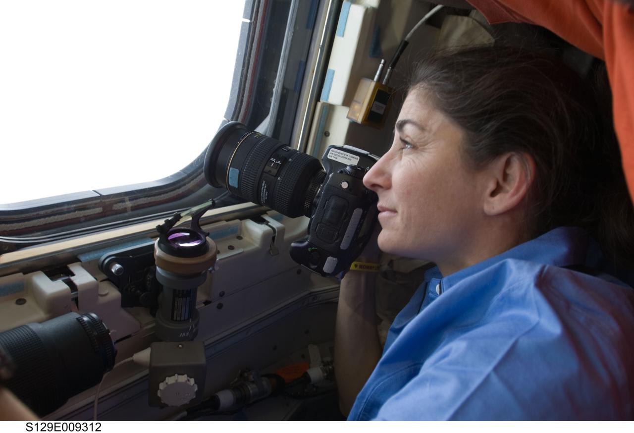 S129-E-009312 (25 Nov. 2009) --- Astronaut Nicole Stott, STS-129 mission specialist, looks through one of Atlantis' aft flight deck windows toward the International Space Station, which she called "home" for almost three months, as the two vehicles continue their relative post-undocking separation. Undocking of the two spacecraft occurred at 3:53 a.m. (CST) on Nov. 25, 2009.