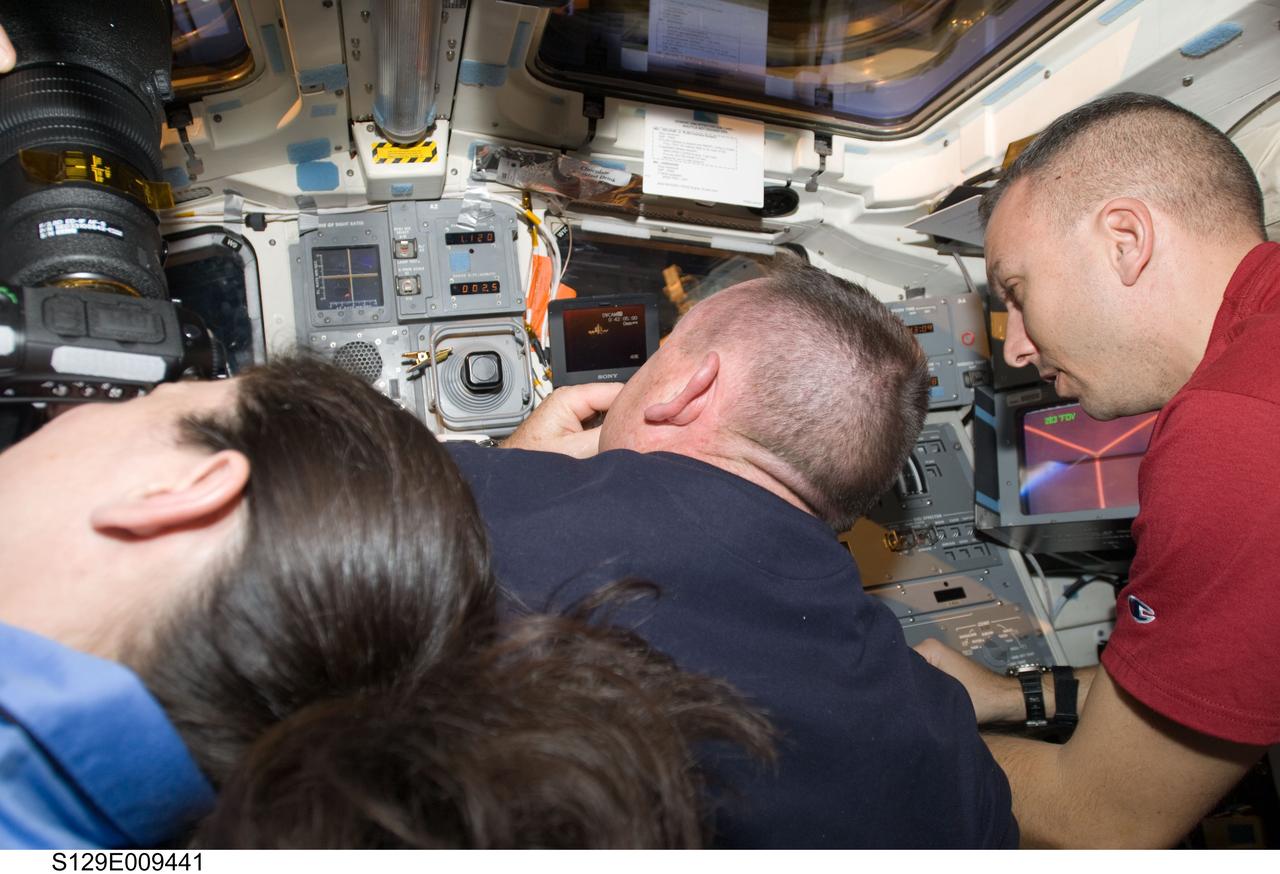 S129-E-009441 (25 Nov. 2009) --- Three members of the STS-129/Atlantis crew take some final glances and photographs of the International Space Station during post-undocking activities aboard the shuttle. Seen on the aft flight deck of Atlantis are, from left, astronauts Nicole Stott, mission specialist; Barry E. Wilmore, pilot; and Randy Bresnik, mission specialist. Bresnik and Wilmore spent almost a full week performing chores in and on the orbital outpost, and Stott just wrapped up almost three months’ duty on it.