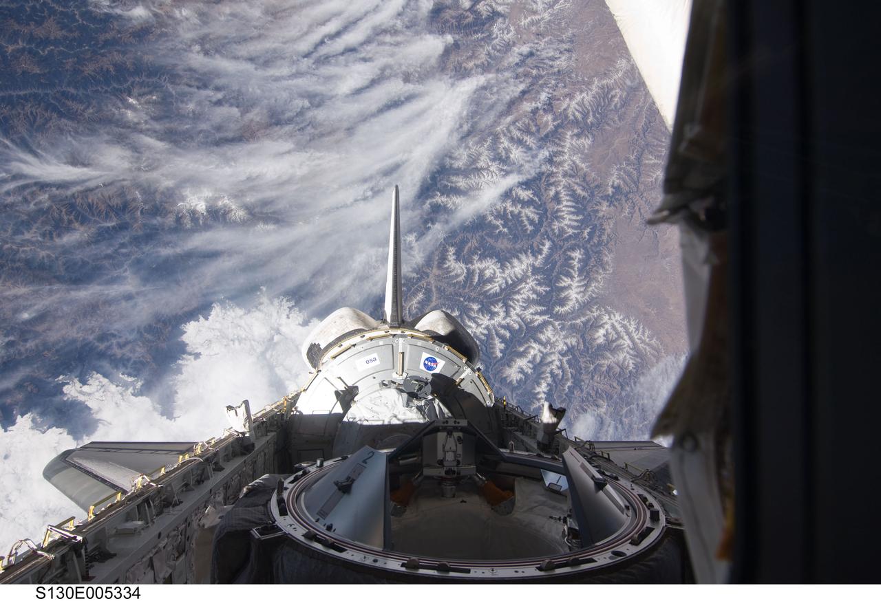 S130-E-005334 (8 Feb. 2010) --- Backdropped by mountainous terrain, the Tranquility node in space shuttle Endeavour’s payload bay, vertical stabilizer, orbital maneuvering system (OMS) pods and docking mechanism are featured in this image photographed by an STS-130 crew member from an aft flight deck window.