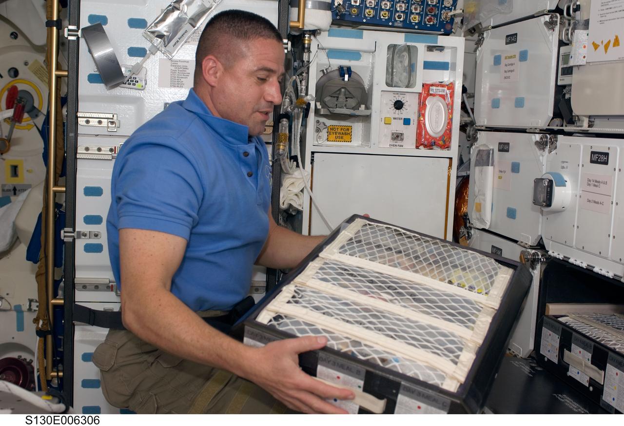 S130-E-006306 (9 Feb. 2010) ---  Astronaut George Zamka, STS-130 mission commander, retrieves a drawer of food on the middeck of the Earth-orbiting space shuttle Endeavour during the early hours of flight day two.