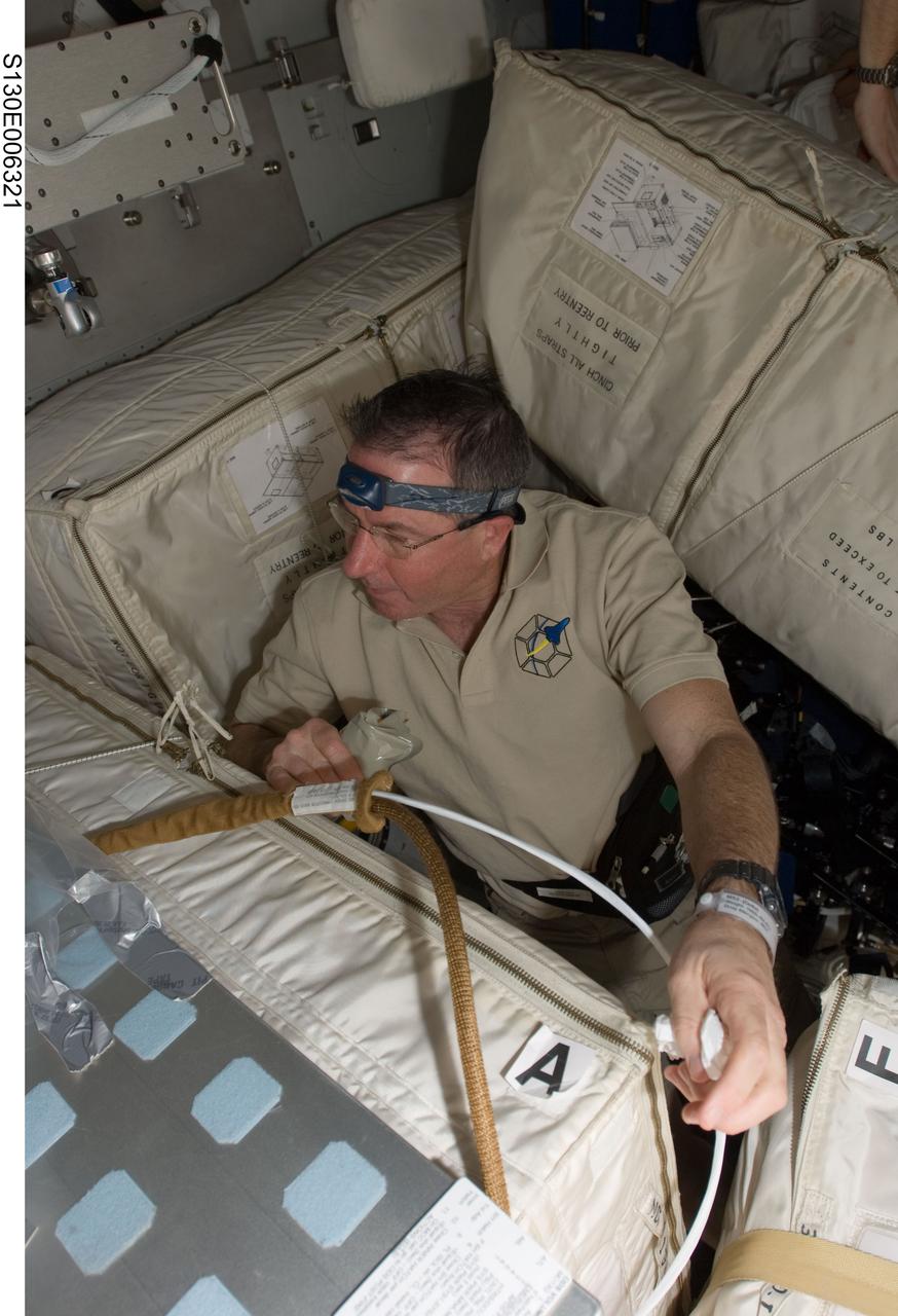 S130-E-006321 (9 Feb. 2010) --- NASA astronaut Stephen Robinson, STS-130 mission specialist, works with stowage containers on the middeck of space shuttle Endeavour during flight day two activities.