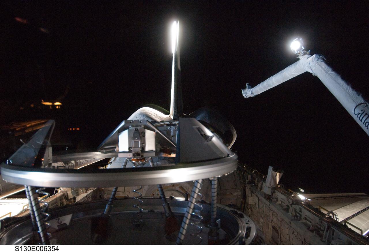S130-E-006354 (9 Feb. 2010) --- Backdropped by the blackness of space, space shuttle Endeavour’s payload bay, docking mechanism (foreground), vertical stabilizer, orbital maneuvering system (OMS) pods, and Remote Manipulator System/Orbiter Boom Sensor System (RMS/OBSS) are featured in this image photographed by an STS-130 crew member from an aft flight deck window.