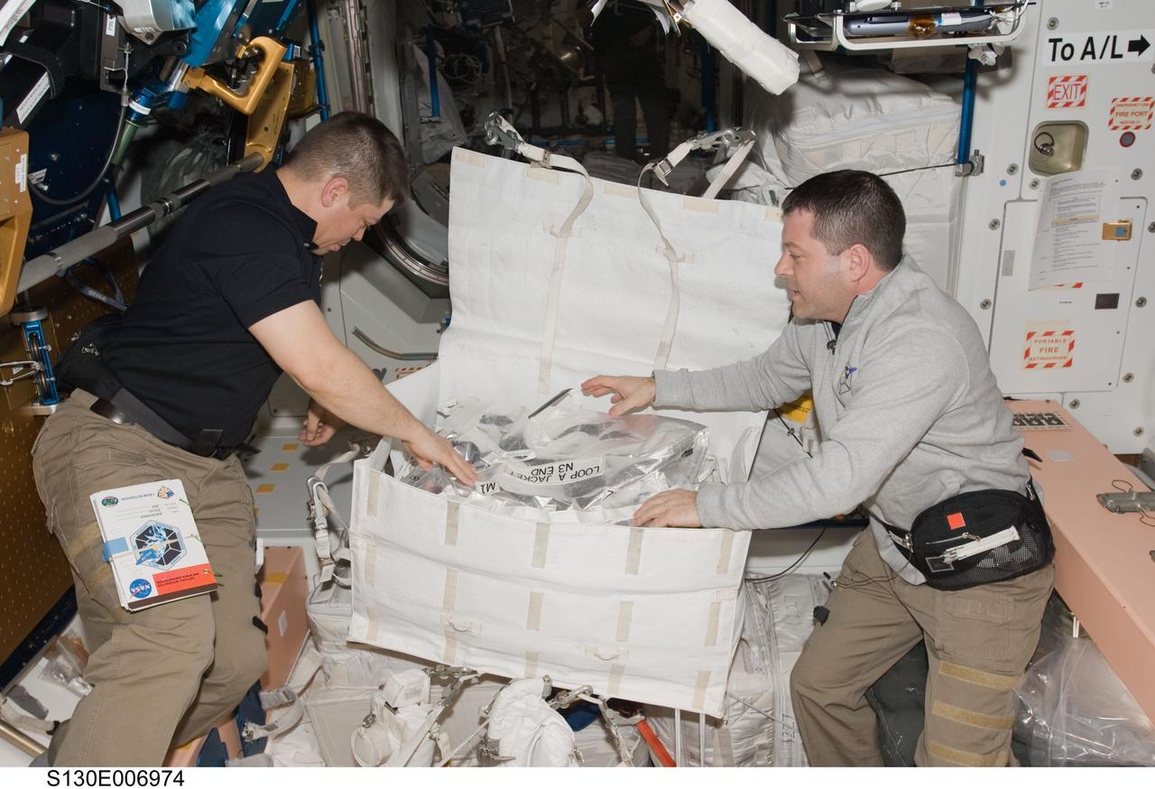 S130-E-006974 (10 Feb. 2010) --- NASA astronauts Robert Behnken (left) and Nicholas Patrick, both STS-130 mission specialists, work with contents of a stowage container in the Unity node of the International Space Station while space shuttle Endeavour remains docked with the station.