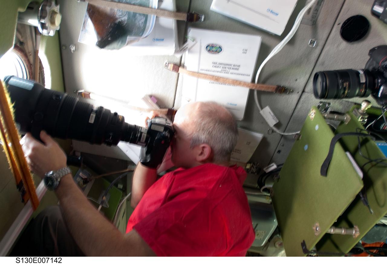 S130-E-007142 (11 Feb. 2010) --- NASA astronaut Jeffrey Williams, Expedition 22 commander, uses a still camera at a window in the Zvezda Service Module of the International Space Station while space shuttle Endeavour (STS-130) remains docked with the station.