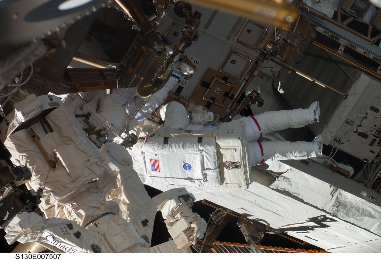 S130-E-007507 (11 Feb. 2010) --- NASA astronauts Robert Behnken and Nicholas Patrick (partially obscured at left), both STS-130 mission specialists, participate in the mission's first session of extravehicular activity (EVA) as construction and maintenance continue on the International Space Station. During the 6-hour, 32-minute spacewalk, Behnken and Patrick relocated a temporary platform from the Special Purpose Dexterous Manipulator, or Dextre, to the station’s truss structure and installed two handles on the robot. Once Tranquility was structurally mated to Unity, the spacewalkers connected heater and data cables that will integrate the new module with the rest of the station’s systems. They also pre-positioned insulation blankets and ammonia hoses that will be used to connect Tranquility to the station’s cooling radiators during the mission’s second spacewalk.