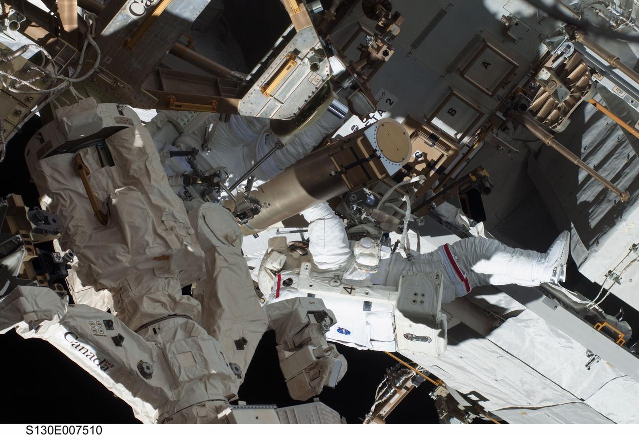 S130-E-007510 (11 Feb. 2010) --- NASA astronauts Robert Behnken and Nicholas Patrick (partially obscured at left), both STS-130 mission specialists, participate in the mission's first session of extravehicular activity (EVA) as construction and maintenance continue on the International Space Station. During the 6-hour, 32-minute spacewalk, Behnken and Patrick relocated a temporary platform from the Special Purpose Dexterous Manipulator, or Dextre, to the station’s truss structure and installed two handles on the robot. Once Tranquility was structurally mated to Unity, the spacewalkers connected heater and data cables that will integrate the new module with the rest of the station’s systems. They also pre-positioned insulation blankets and ammonia hoses that will be used to connect Tranquility to the station’s cooling radiators during the mission’s second spacewalk.