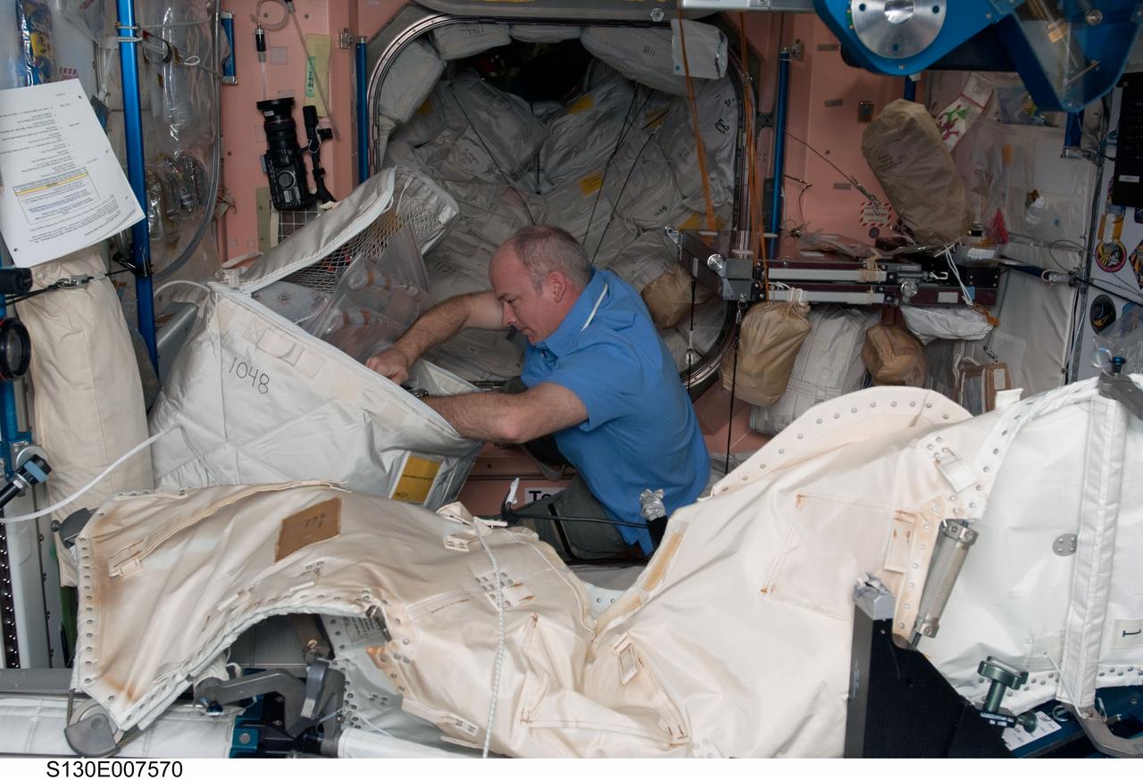 S130-E-007570 (13 Feb. 2010) --- NASA astronaut Jeffrey Williams, Expedition 22 commander, retrieves items from a stowage bag in the Unity node of the International Space Station while space shuttle Endeavour (STS-130) remains docked with the station.