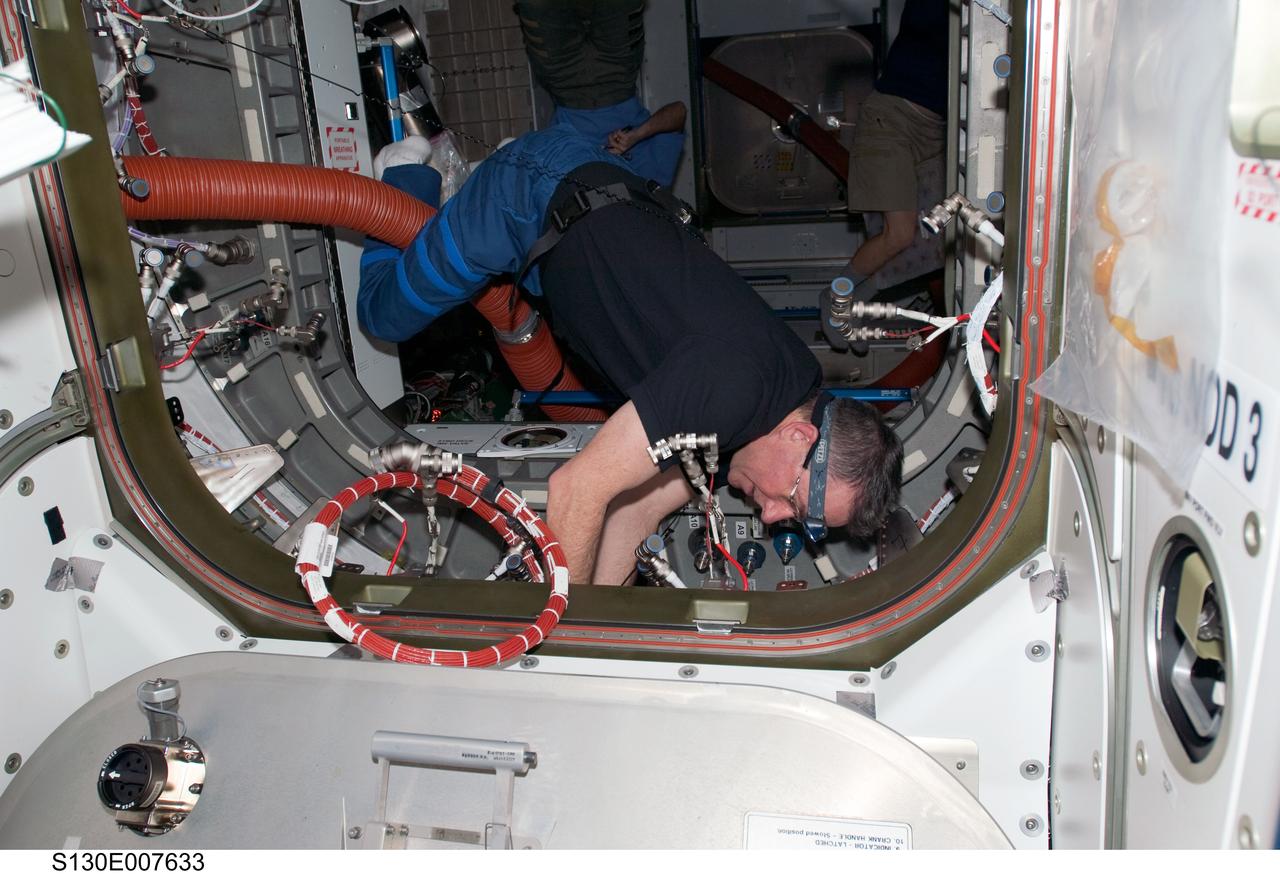 S130-E-007633 (13 Feb. 2010) --- NASA astronaut Stephen Robinson, STS-130 mission specialist, works in the vestibule between the Unity node and the newly-installed Tranquility node of the International Space Station while space shuttle Endeavour remains docked with the station.