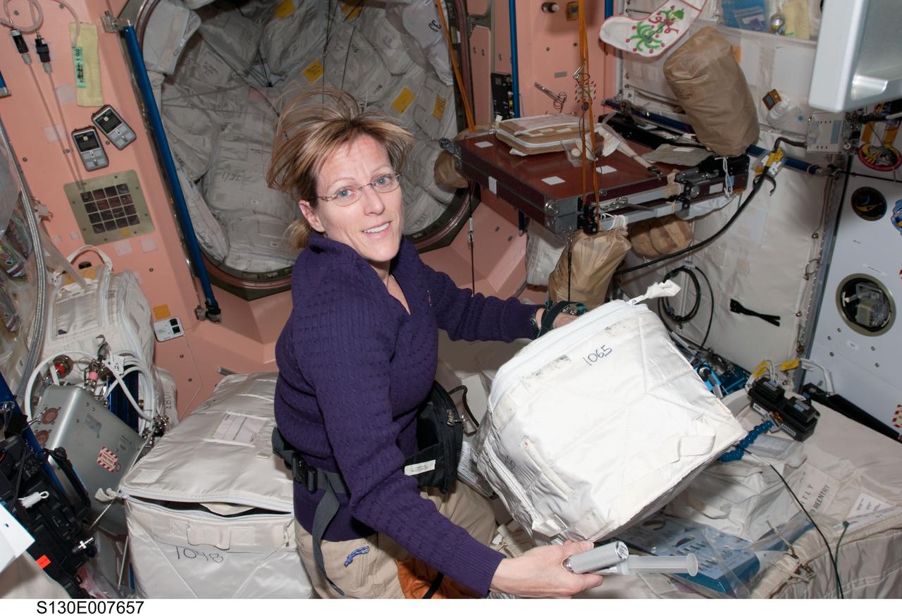 S130-E-007657 (13 Feb. 2010) --- NASA astronaut Kathryn Hire, STS-130 mission specialist, works with stowage containers in the Unity node of the International Space Station while space shuttle Endeavour remains docked with the station.