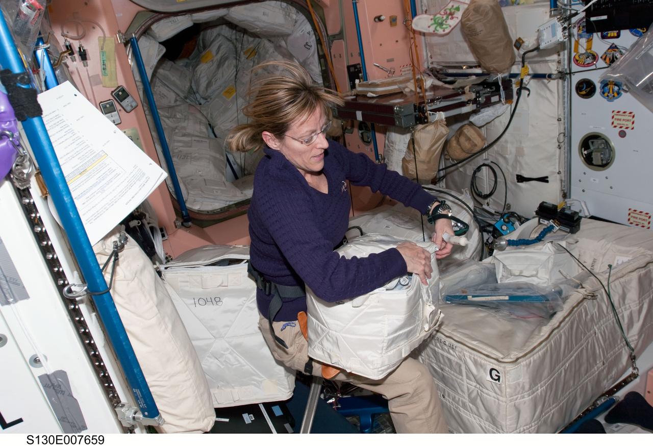 S130-E-007659 (13 Feb. 2010) --- NASA astronaut Kathryn Hire, STS-130 mission specialist, works with stowage containers in the Unity node of the International Space Station while space shuttle Endeavour remains docked with the station.
