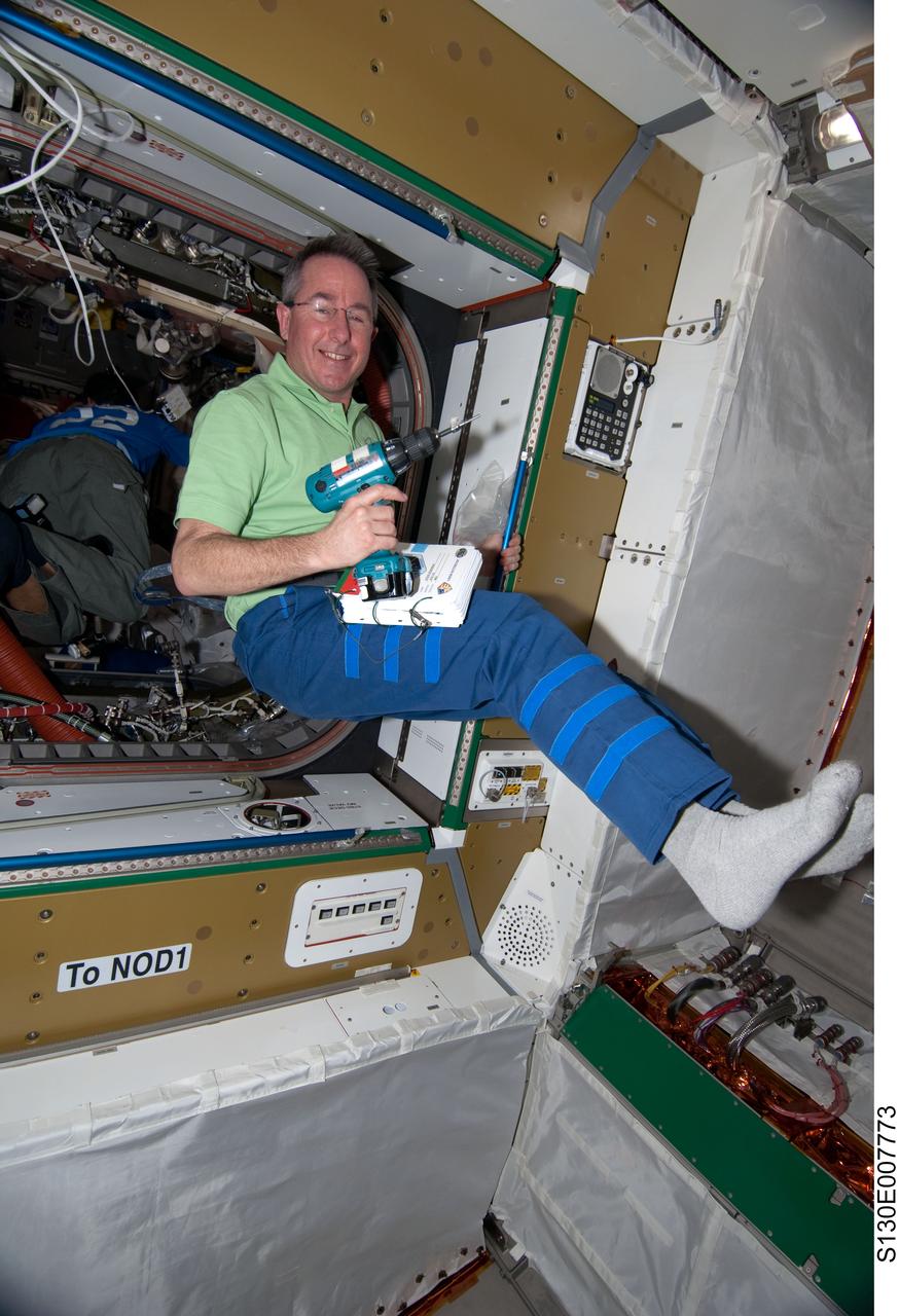 S130-E-007773 (14 Feb. 2010) --- NASA astronaut Stephen Robinson, STS-130 mission specialist, holds a drill while floating freely in the newly-installed Tranquility node of the International Space Station while space shuttle Endeavour remains docked with the station.