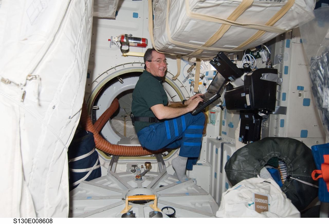 S130-E-008608 (16 Feb. 2010) --- NASA astronaut Stephen Robinson, STS-130 mission specialist, uses a computer on the middeck of space shuttle Endeavour while docked with the International Space Station.
