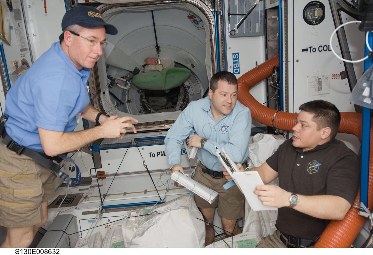 S130-E-008632 (16 Feb. 2010) --- NASA astronauts Stephen Robinson (left), Nicholas Patrick and Robert Behnken, all STS-130 mission specialists, work in the Harmony node of the International Space Station while space shuttle Endeavour remains docked with the station.