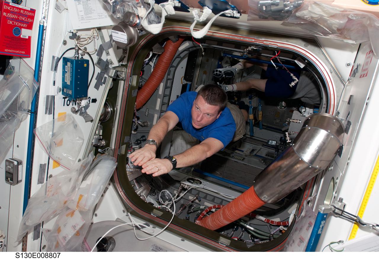 S130-E-008807 (16 Feb. 2010) --- NASA astronaut Terry Virts, STS-130 pilot, floats through a hatch between the Unity and Tranquility nodes of the International Space Station while space shuttle Endeavour remains docked with the station.