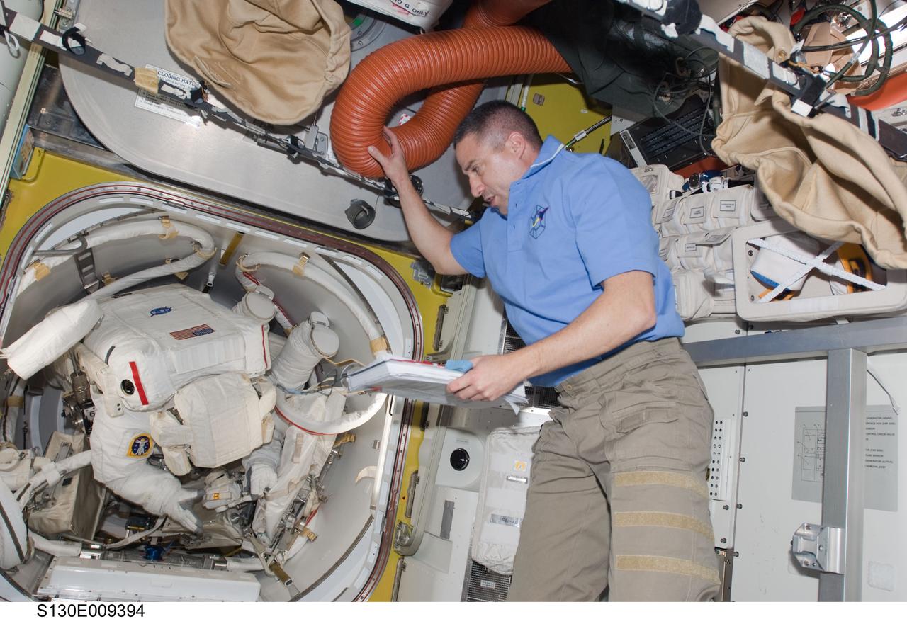S130-E-009394 (16 Feb. 2010) --- NASA astronaut George Zamka, STS-130 commander, is pictured in the Quest airlock of the International Space Station as astronauts Robert Behnken and Nicholas Patrick, both mission specialists, prepare to exit the airlock to begin the mission’s third and final session of extravehicular activity (EVA).