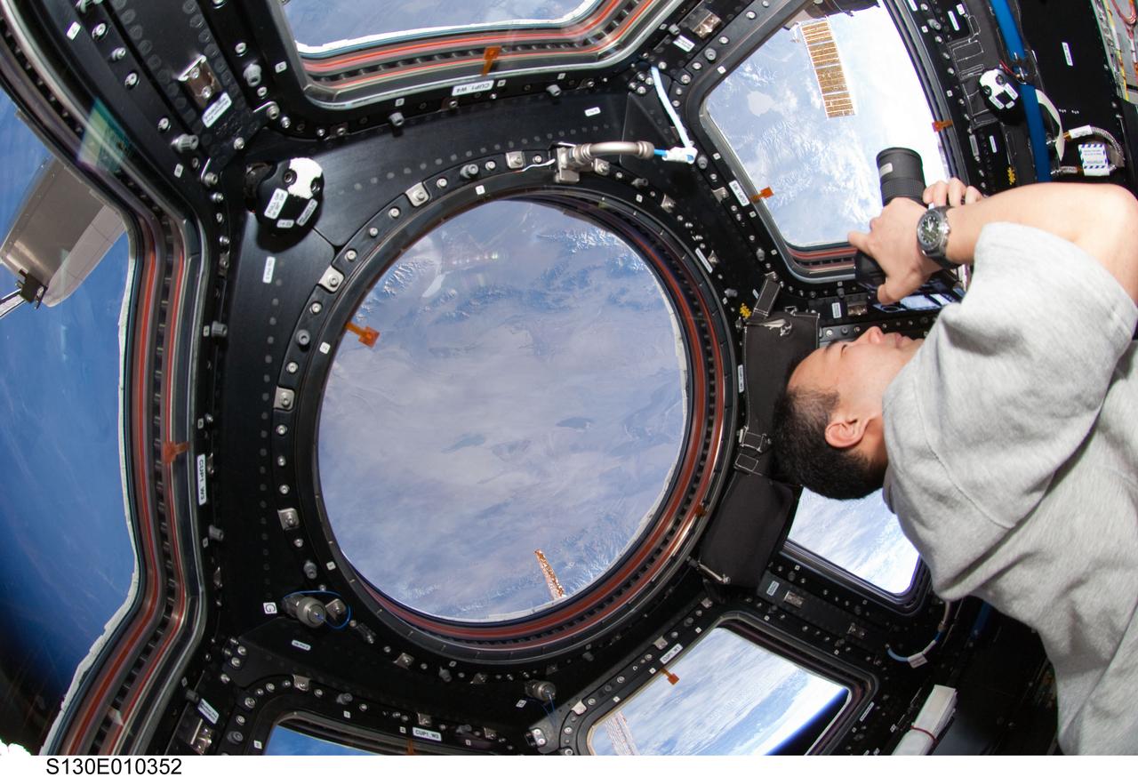 S130-E-010352 (18 Feb. 2010) --- Japan Aerospace Exploration Agency (JAXA) astronaut Soichi Noguchi, Expedition 22 flight engineer, uses a still camera at a window in the Cupola of the International Space Station while space shuttle Endeavour (STS-130) remains docked with the station.