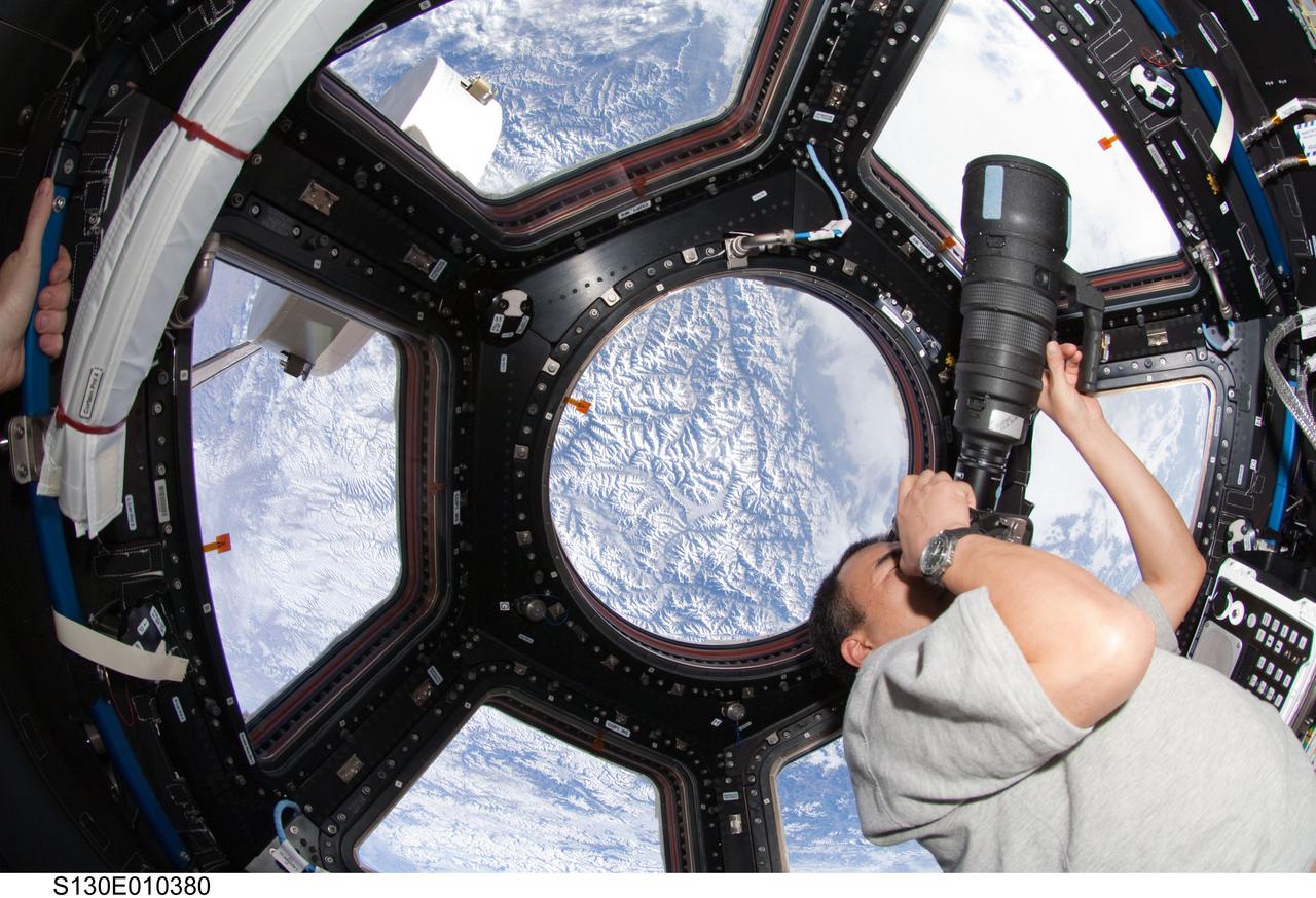 S130-E-010380 (18 Feb. 2010) --- Japan Aerospace Exploration Agency (JAXA) astronaut Soichi Noguchi, Expedition 22 flight engineer, uses a still camera to photograph the topography of a point on Earth from a window in the Cupola of the International Space Station while space shuttle Endeavour (STS-130) remains docked with the station.