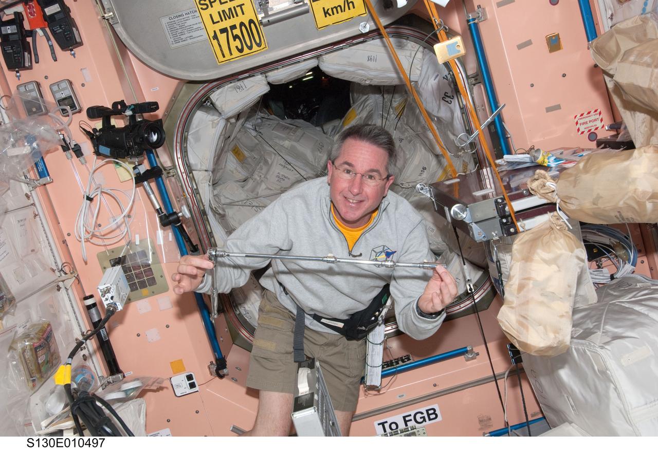 S130-E-010497 (18 Feb. 2010) --- NASA astronaut Stephen Robinson, STS-130 mission specialist, holds a tool in the Unity node of the International Space Station while space shuttle Endeavour remains docked with the station.